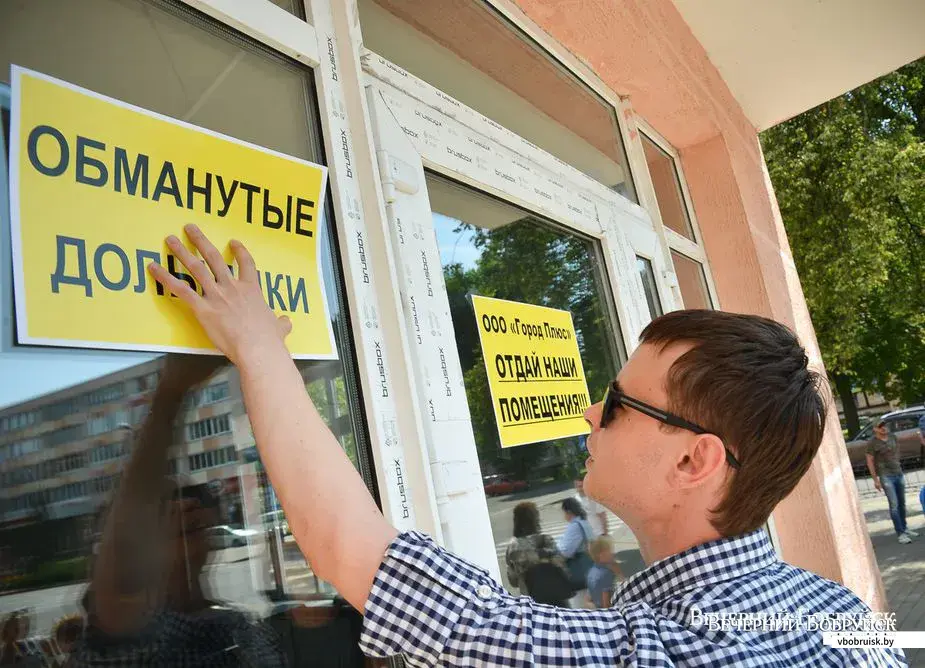 Дольщики ООО «Город плюс» вывешивают плакаты на помещениях дома на Социалистической, 123. Фото Александра ЧУГУЕВА из архива «ВБ».