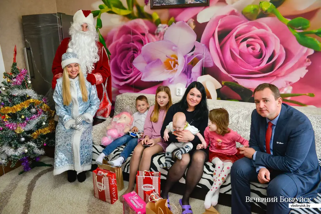 20.12.2019. Дед Мороз со Снегурочкой и директор ОАО «Красный Пищевик» Сергей Анюховский вручают новогодние подарки детям из многодетной семьи Светланы Филипчик
