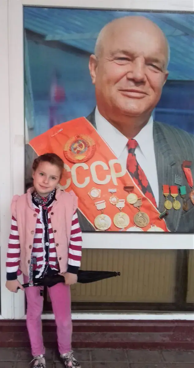 Внучка Полина рядом с портретом дедушки.