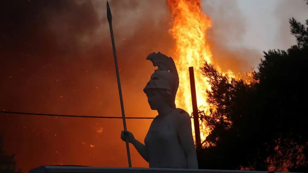 Статуя богини Афины во время пожара в пригороде Варибоби к северу от Афин. Фото: Reuters.