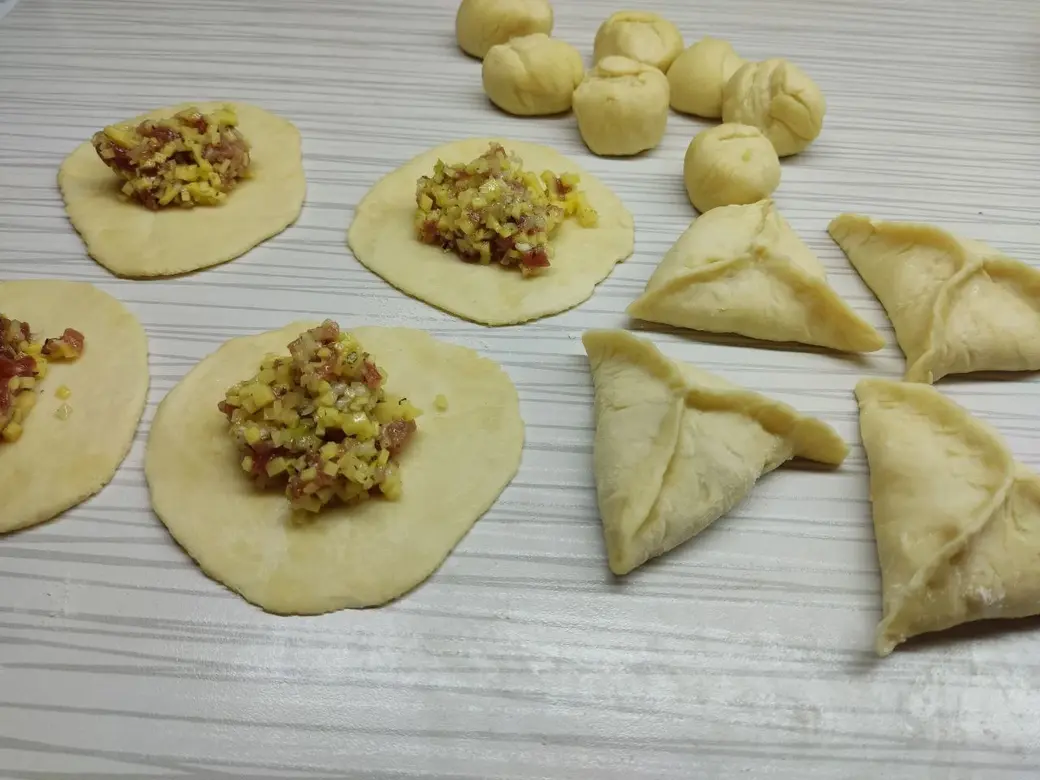 Кусочки теста тонко раскатать, выложить на каждый десертную ложку фарша и залепить края